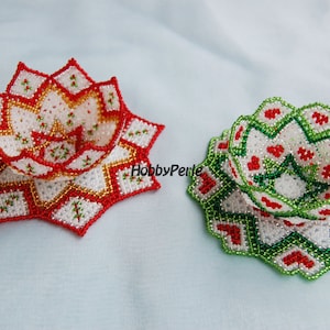 May include: Two beaded Christmas ornaments in the shape of a star. One ornament is red and gold, the other is green and red.