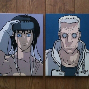 以下が含まれることがあります： SF アニメのキャラクターを描いた額装されたイラストが2つ。左側のキャラクターは、白いヘッドバンドと白い衣服を着た、短い黒髪の女性。右側のキャラクターは、白いジャケットと黒いシャツを着た、短い白髪の男性。