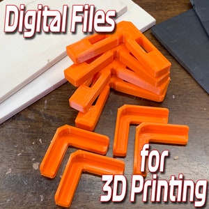 Puede incluir: Archivos digitales para impresión 3D de soportes de esquina de color naranja. Los soportes están apilados sobre una superficie de madera.