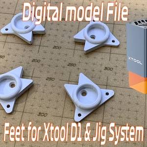 Puede incluir: Se muestran cuatro pies blancos en forma de estrella con centros circulares y un grabador láser. También se ve el texto "Digital model File" y "Feet for Xtool D1 & Jig System". El grabador láser es gris con la marca "XTOOL".