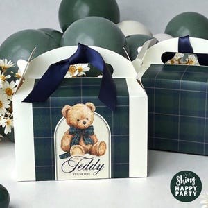 Puede incluir: Cajas de regalo a cuadros verdes y blancos con asas de cinta azul marino. Cada caja presenta una ilustración de oso de peluche con el texto "Teddy Turns One". Globos verdes y flores blancas en el fondo.