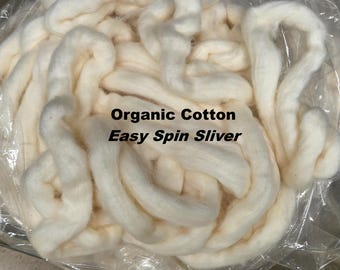 May include: Close-up of a pile of off-white organic cotton sliver. The text "Organic Cotton Easy Spin Sliver" is printed on the image. The cotton appears soft and fluffy, ideal for spinning and crafting projects.