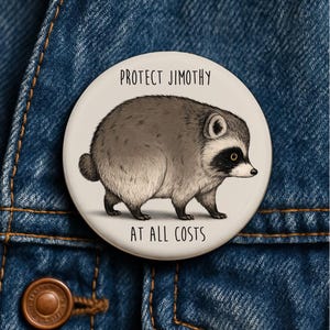 Op de afbeelding: Een ronde button met een crèmekleurige achtergrond en een zwart-witte illustratie van een ronde wasbeer. De tekst "PROTECT JIMOTHY" staat in het zwart boven de wasbeer gedrukt en "AT ALL COSTS" staat in het zwart eronder gedrukt.