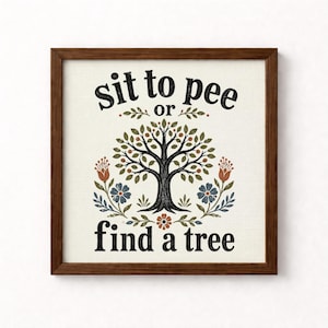 May include: A square wall sign in a dark brown wooden frame featuring a cream-colored background. The text reads sit to pee or find a tree in black lettering. A central black tree illustration is surrounded by colorful floral and leaf motifs.