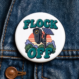 May include: A round white pinback button featuring a graphic of a security camera mounted on a pole with a small solar panel. Below the camera are green bushes and a sunset background. The text FLOCK OFF is printed in large teal letters.