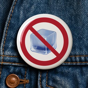 Pode incluir: Um botão branco com um símbolo de proibição vermelho sobre uma ilustração de cubo de gelo azul. O botão está sobre um fundo de jaqueta jeans.