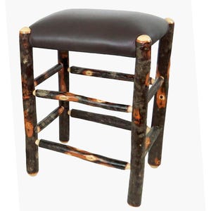 May include: A brown leather-padded stool with a rustic log frame. The stool has three horizontal supports and a natural wood finish.
