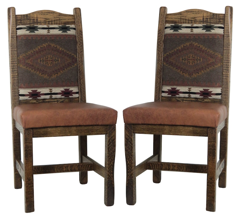 May include: Two wooden dining chairs with brown leather seats and patterned fabric backrests. The fabric features a southwestern design in shades of red, brown, and white.