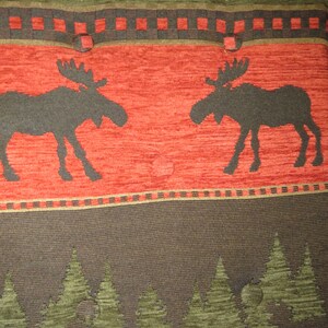 May include: Red, green, and brown patterned fabric with two moose silhouettes. The fabric has a repeating pattern of small squares and leaves.
