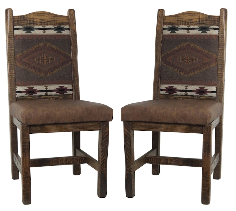 May include: Two wooden dining chairs with brown faux leather seats and woven patterned backs. The chairs have a rustic, Southwestern style.