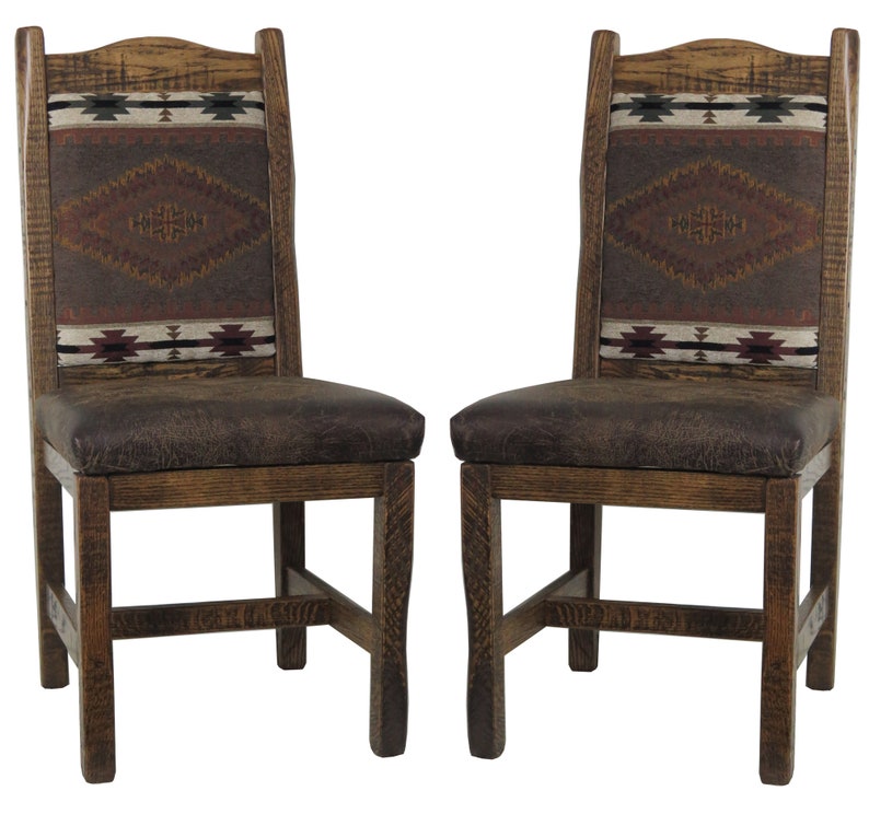 May include: Two wooden dining chairs with brown leather seats and patterned fabric backrests. The chairs have a rustic, Southwestern style.