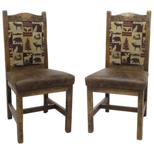 May include: A pair of wooden chairs with brown leather seats and high backrests. The backrests feature a rectangular fabric panel with a repeating pattern of bears, moose, deer, fish, and pine trees in shades of brown, tan, and dark red.