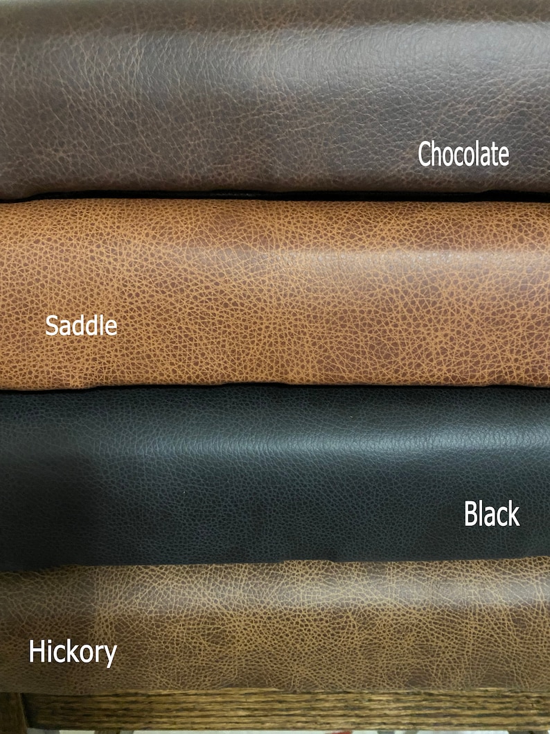 May include: Four stacked rolls of textured material in different colors. The top roll is dark brown labeled Chocolate, the second is tan labeled Saddle, the third is black labeled Black, and the bottom roll is light brown labeled Hickory.