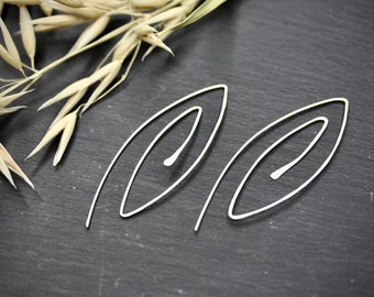 Könnte beinhalten: Ein Paar silberne Ohrringe mit einem schlichten, modernen Design. Die Ohrringe sind in Form von länglichen Ovalen mit einem kleineren Oval im Inneren gestaltet.