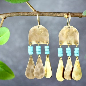 May include: A pair of gold-toned dangle earrings with turquoise beads and a hammered metal design.