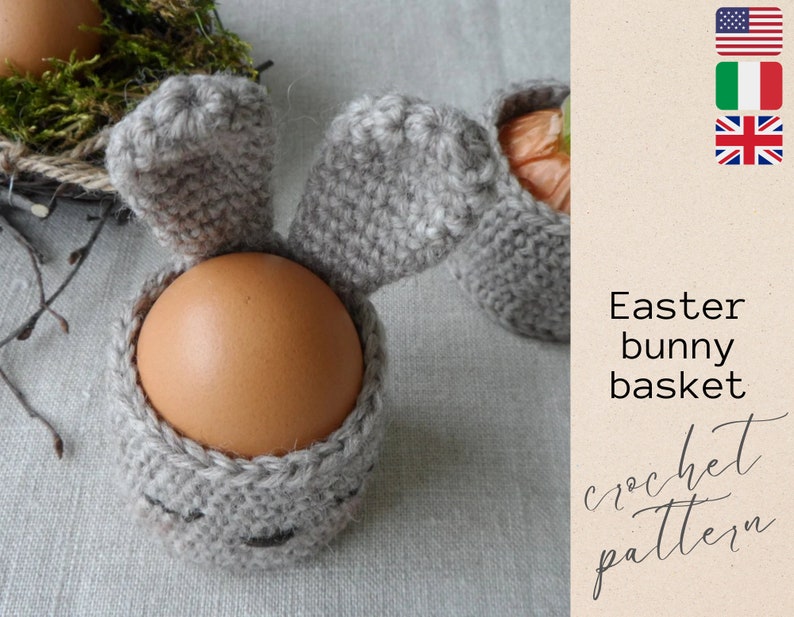 May include: A crochet Easter bunny basket with long floppy ears, made in a light gray color, holding a brown egg. The basket is a great way to decorate for Easter and can be used to hold small gifts or treats.