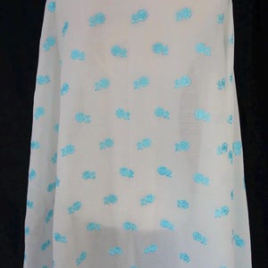 May include: White fabric with a repeating pattern of light blue embroidered flowers.
