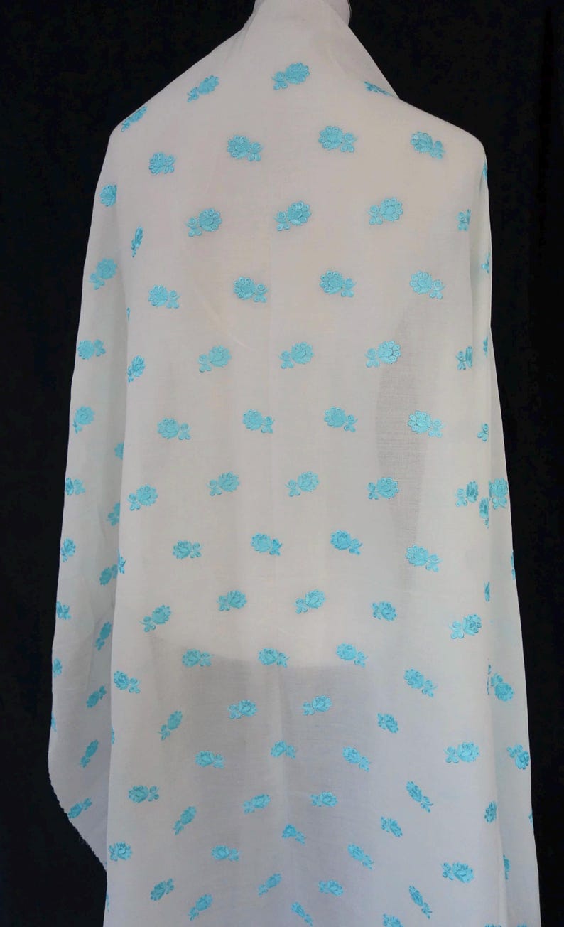 May include: White fabric with a repeating pattern of light blue embroidered flowers.
