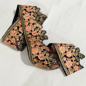 May include: A navy blue lace trim with pink and gold floral embroidery. The trim has a scalloped edge and is perfect for adding a touch of elegance to any project.