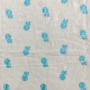 May include: White fabric with a repeating pattern of light blue embroidered flowers.