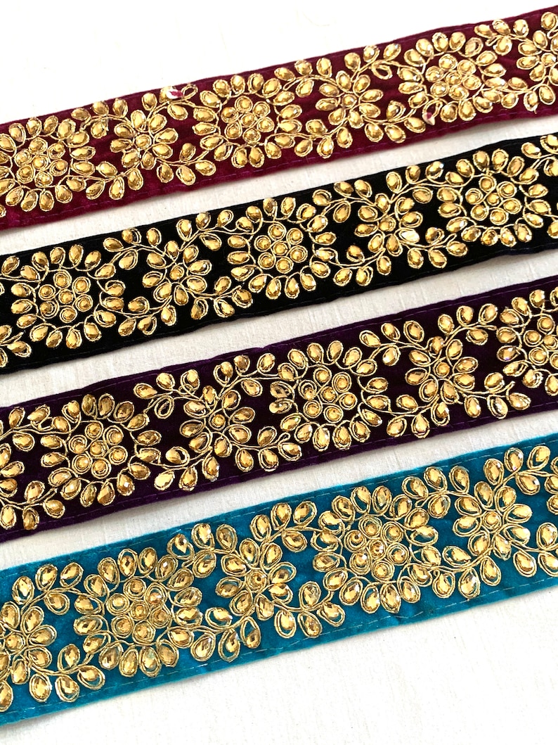 May include: Four velvet ribbon trims with gold embroidery and rhinestones. The trims are in burgundy, black, purple, and teal.