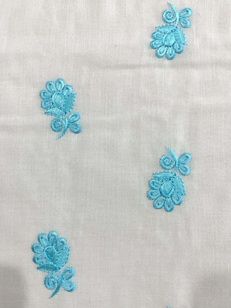 May include: White fabric with a repeating pattern of blue embroidered flowers.