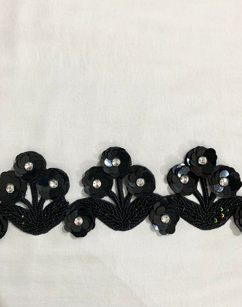 May include: Black beaded trim with a floral design. The trim features black sequins and small rhinestones.