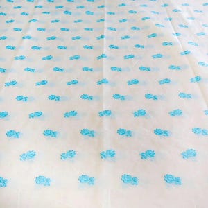 May include: White fabric with a repeating pattern of small blue floral designs.