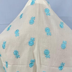 May include: White fabric with a light blue floral embroidery pattern.