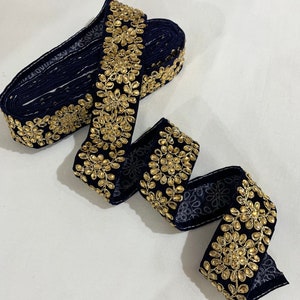 May include: Navy blue trim with gold embellishments. The trim features a repeating pattern of small gold circles surrounded by gold leaves.