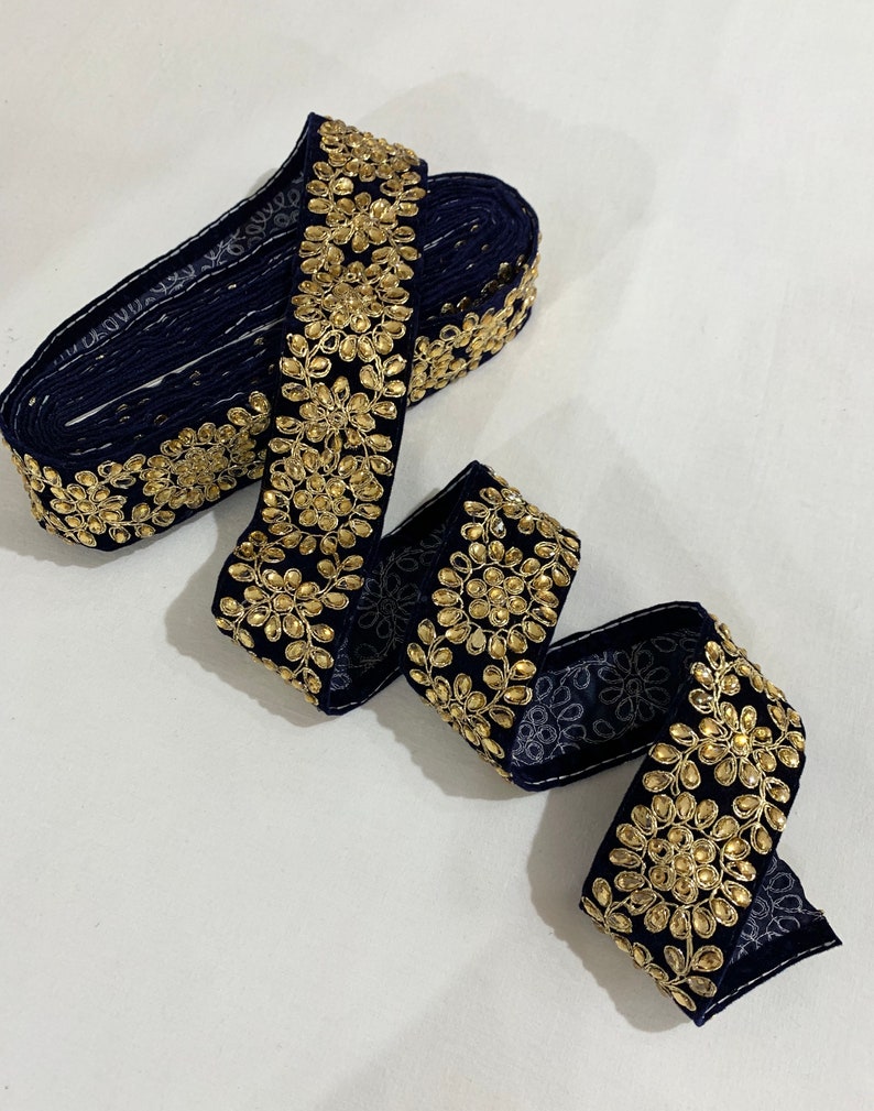 May include: Navy blue trim with gold embellishments. The trim features a repeating pattern of small gold circles surrounded by gold leaves.