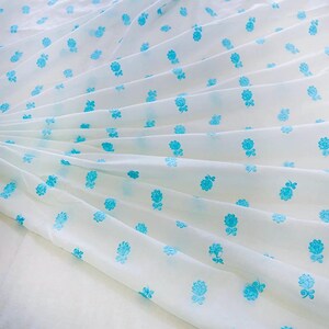 May include: White fabric with a repeating pattern of small blue flowers.