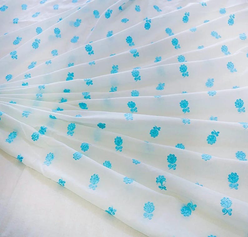 May include: White fabric with a repeating pattern of small blue flowers.