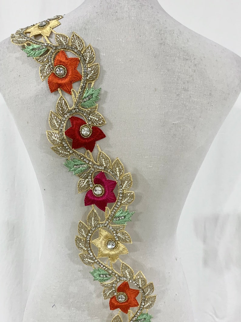 May include: Gold trim lace with red, orange, and pink flowers and clear rhinestones.