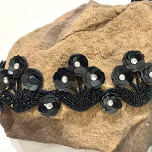 May include: Black beaded trim with black flower embellishments and clear rhinestones.