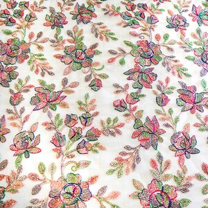 May include: White fabric with a floral pattern embroidered with iridescent beads in shades of pink, green, and blue.