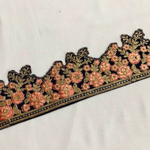 May include: Black velvet trim with pink and gold floral embroidery. The trim has a scalloped edge and a repeating pattern of flowers and leaves.