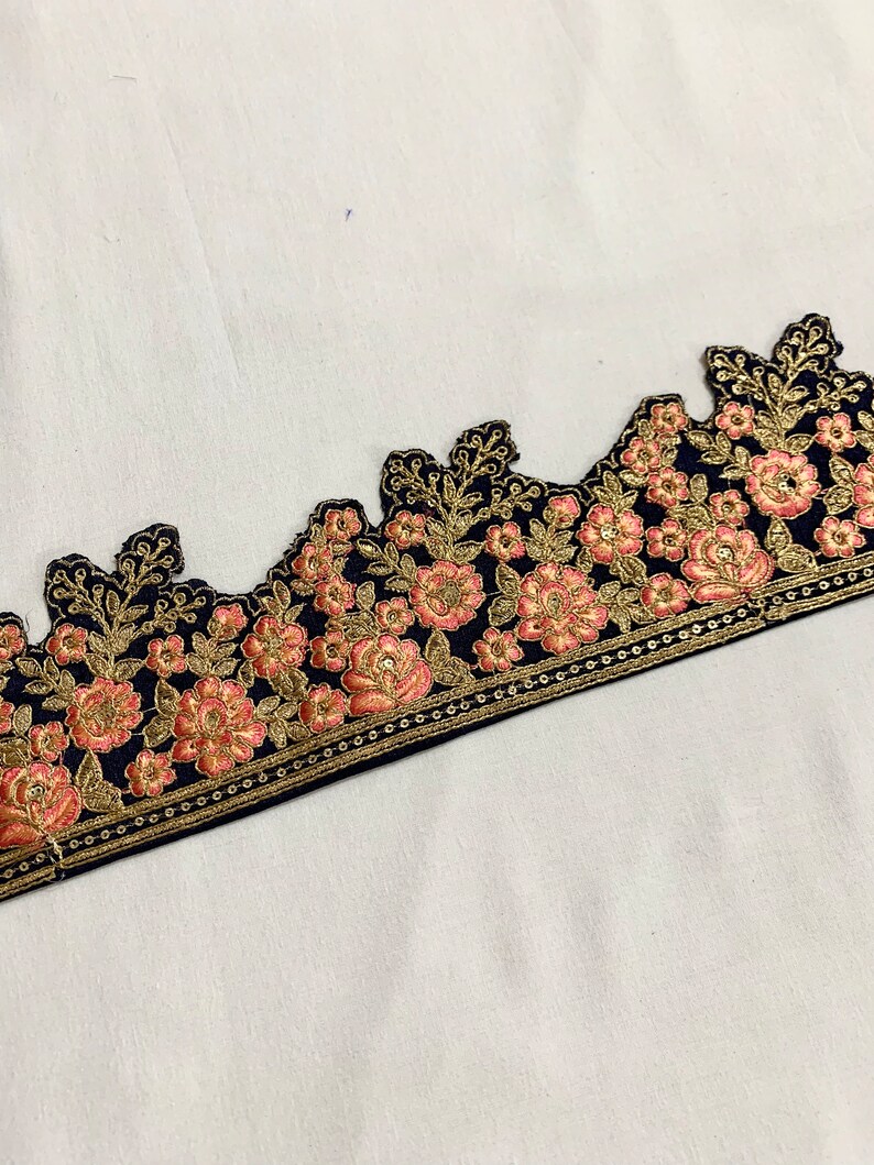 May include: Black velvet trim with pink and gold floral embroidery. The trim has a scalloped edge and a repeating pattern of flowers and leaves.