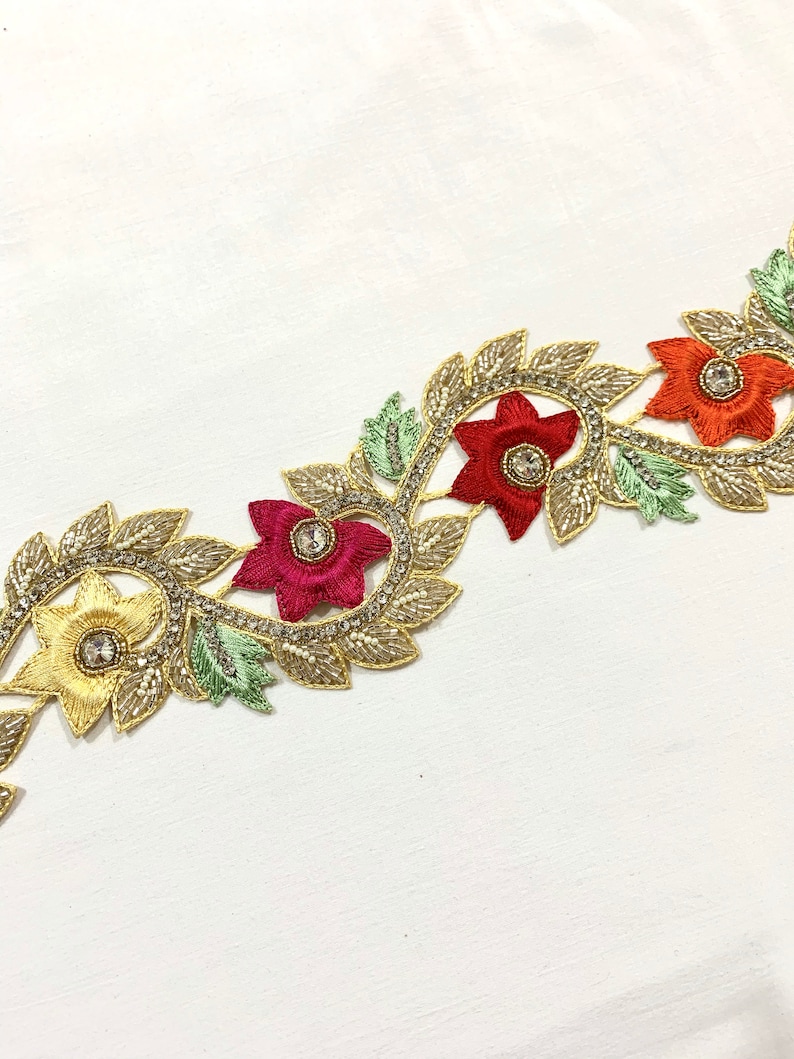 May include: Gold, red, and yellow floral trim with beaded accents. The trim features a repeating pattern of flowers and leaves.