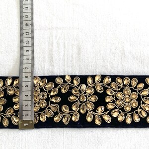 May include: A navy blue velvet trim with gold embroidery and rhinestones. The trim is approximately 2 inches wide.