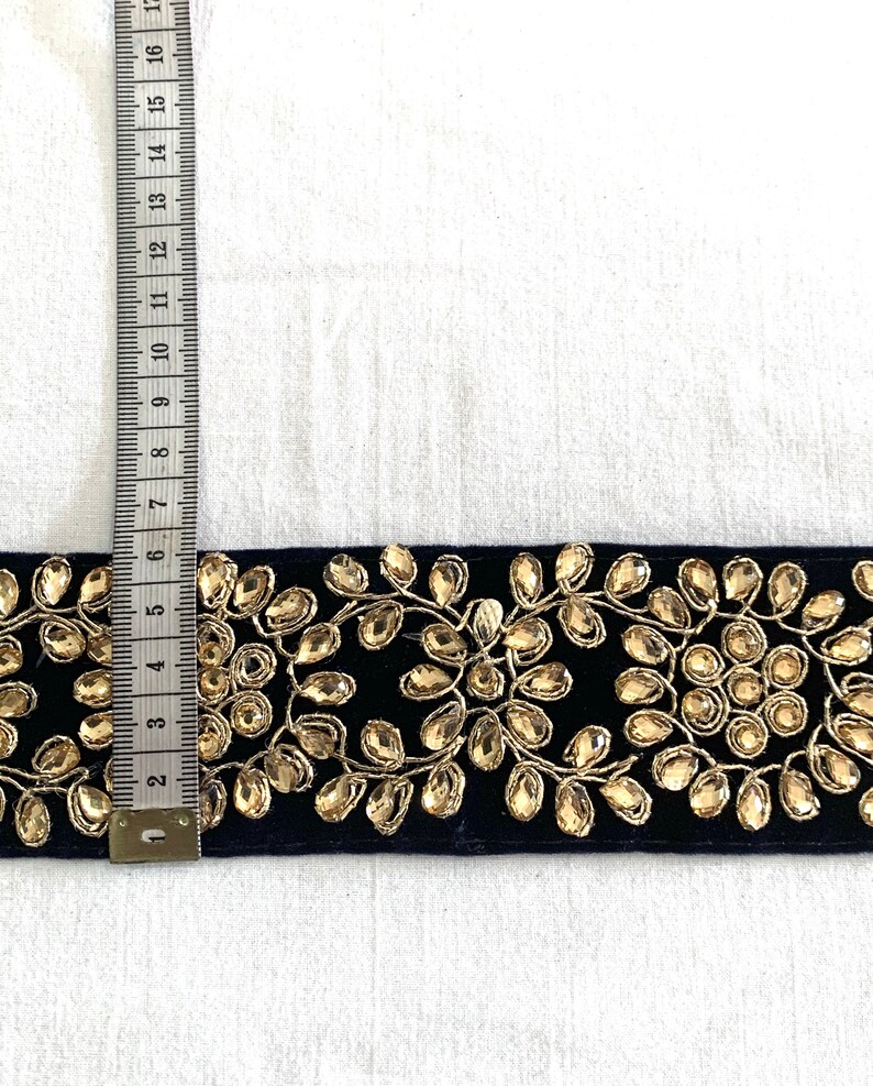 May include: A navy blue velvet trim with gold embroidery and rhinestones. The trim is approximately 2 inches wide.