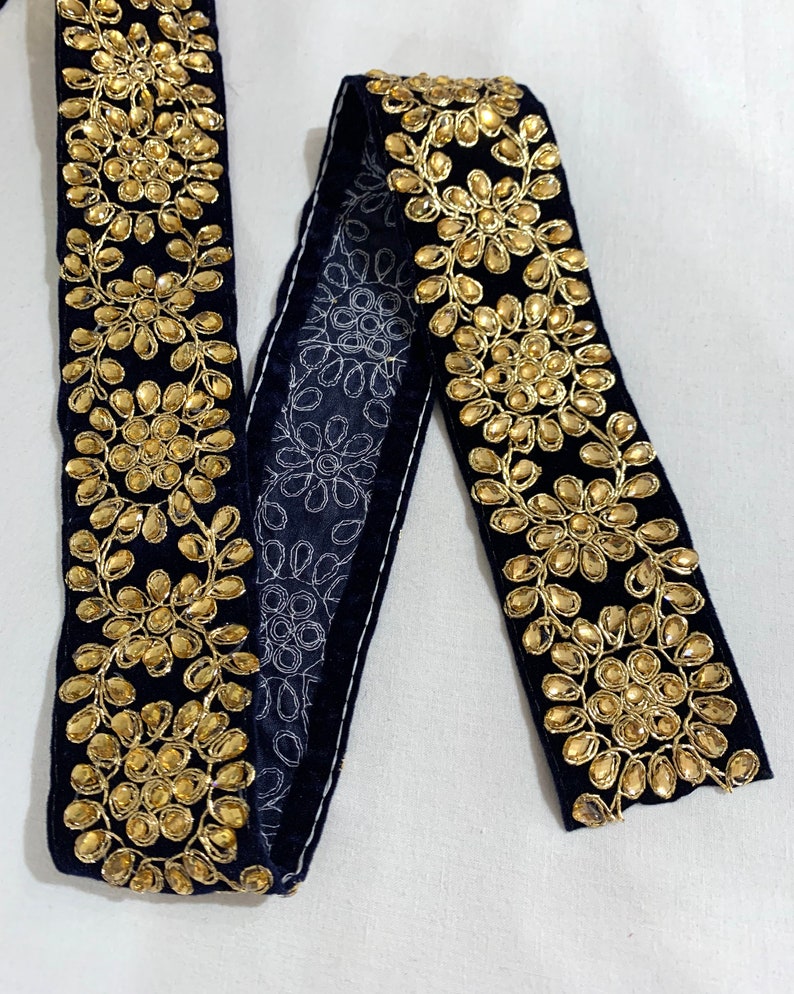 May include: Black velvet trim with gold embroidered floral designs and rhinestones.