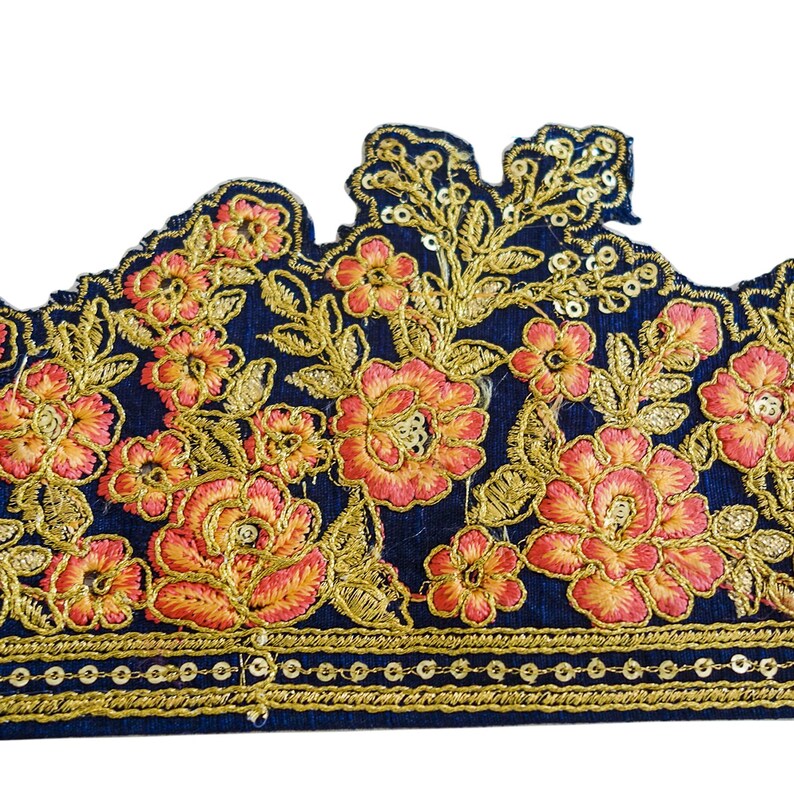 May include: A navy blue fabric trim with gold and orange embroidered floral designs. The trim has a scalloped edge and a row of gold sequins along the bottom.