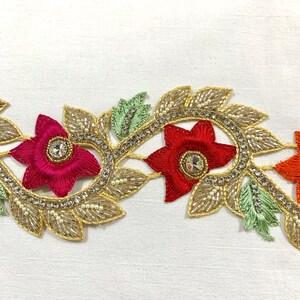 May include: Gold embroidered trim with red, orange, and green floral designs. The trim features small pearl-like beads and rhinestones.