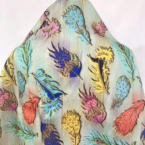 May include: A light beige fabric with a colorful feather pattern. The feathers are in shades of blue, yellow, pink, and red. The fabric has a subtle sheen.