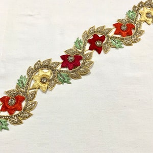 May include: Gold embroidered trim with red, orange, and yellow flowers and green leaves. The trim features sparkling rhinestones in the center of each flower.