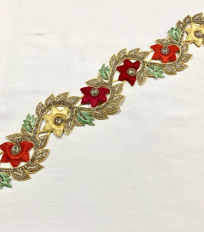 May include: Gold embroidered trim with red, orange, and yellow flowers and green leaves. The trim features sparkling rhinestones in the center of each flower.