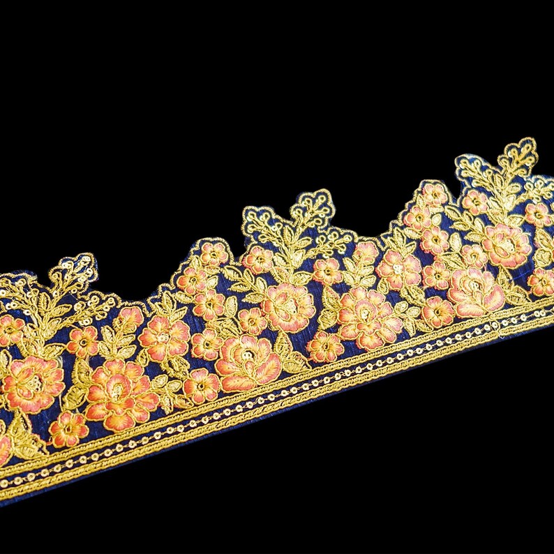 May include: A navy blue fabric trim with gold and peach floral embroidery. The trim has a scalloped edge and a beaded border.