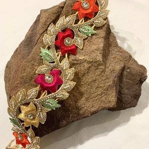 May include: Gold, red, and green floral trim with beaded accents and rhinestones. The trim features a repeating pattern of flowers and leaves.