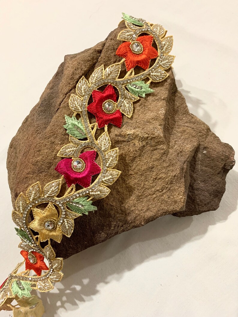 May include: Gold, red, and green floral trim with beaded accents and rhinestones. The trim features a repeating pattern of flowers and leaves.